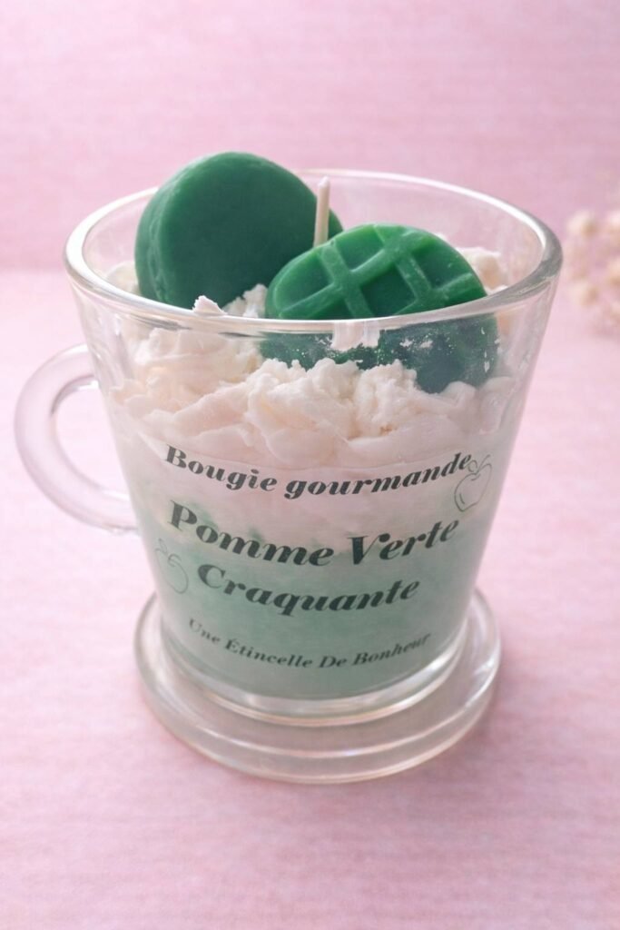 Bougie artisanale parfumée dans un petit verre, décorée de fleurs en cire de soja vertes et blanches
