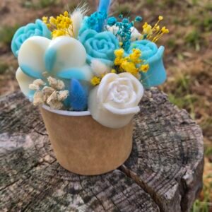 Composition florale artisanale dans un petit pot en bois, décorée de fleurs en cire de soja parfumée bleues et blanches et de fleurs séchées jaunes