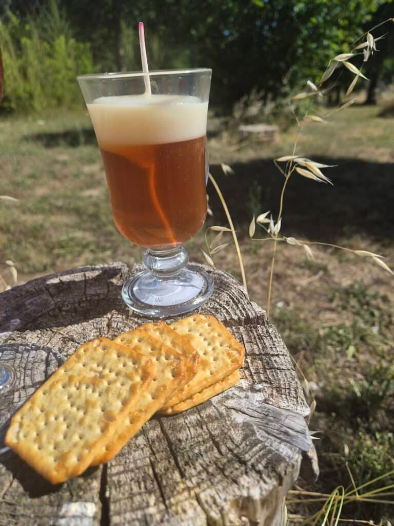 Bougie gourmande artisanale en forme de verre de bière ambrée avec mousse blanche, accompagnée de biscuits décoratifs