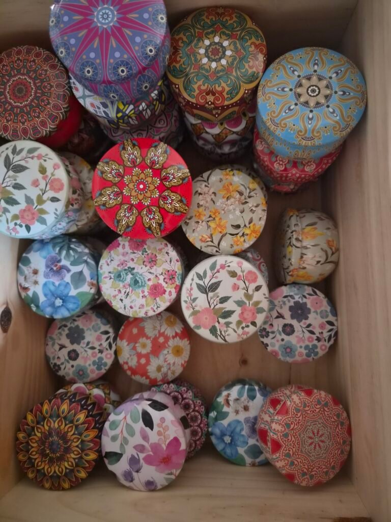 Collection de bougies parfumées artisanales dans des contenants ronds décorés de motifs floraux colorés